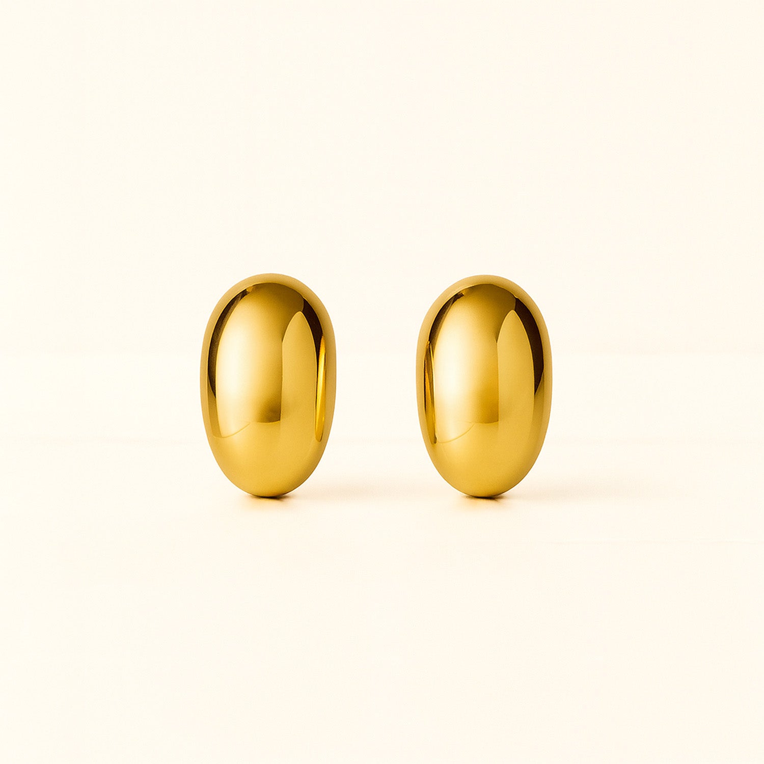 Pair of gold earrings on a light beige background