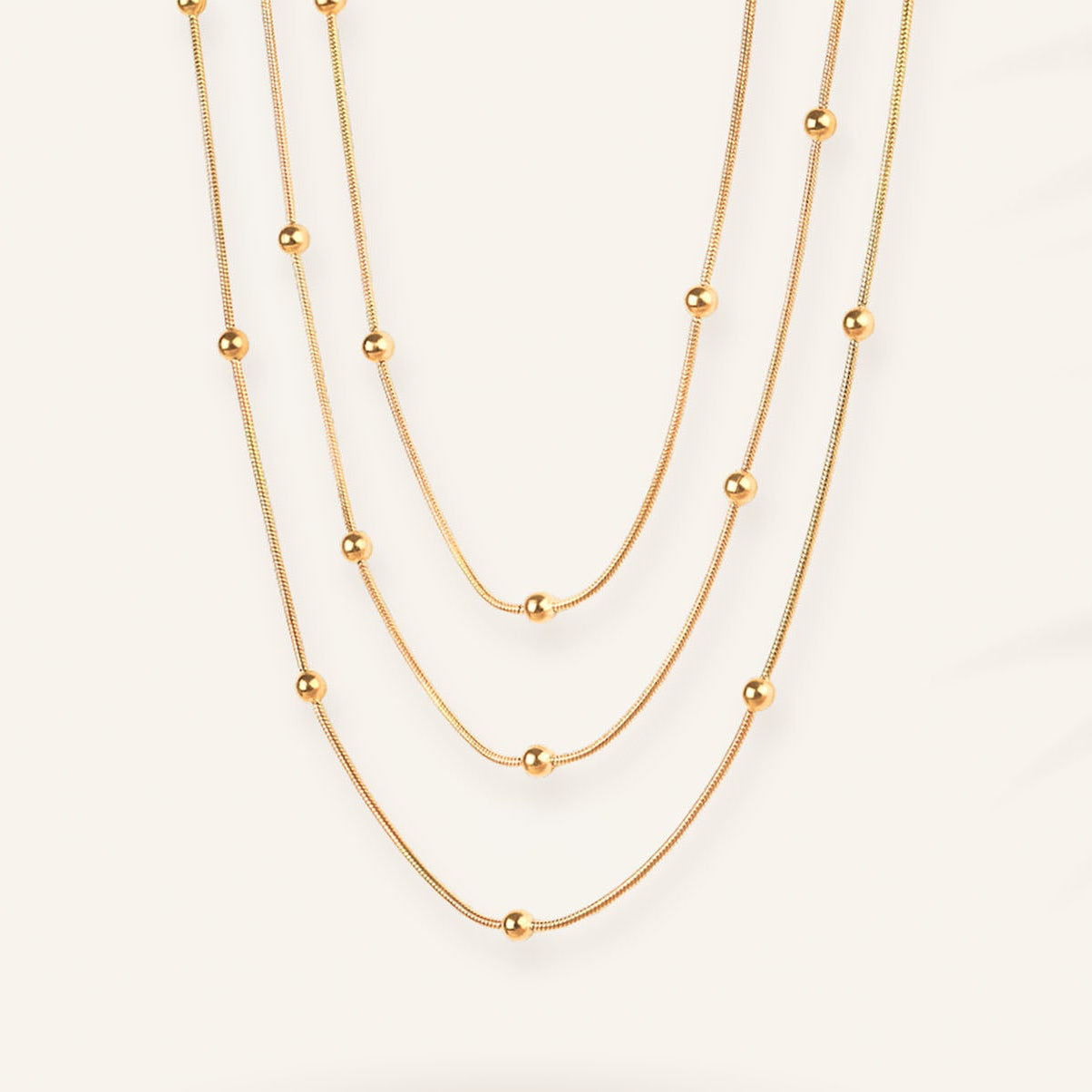Three gold necklaces of different lengths on a white background